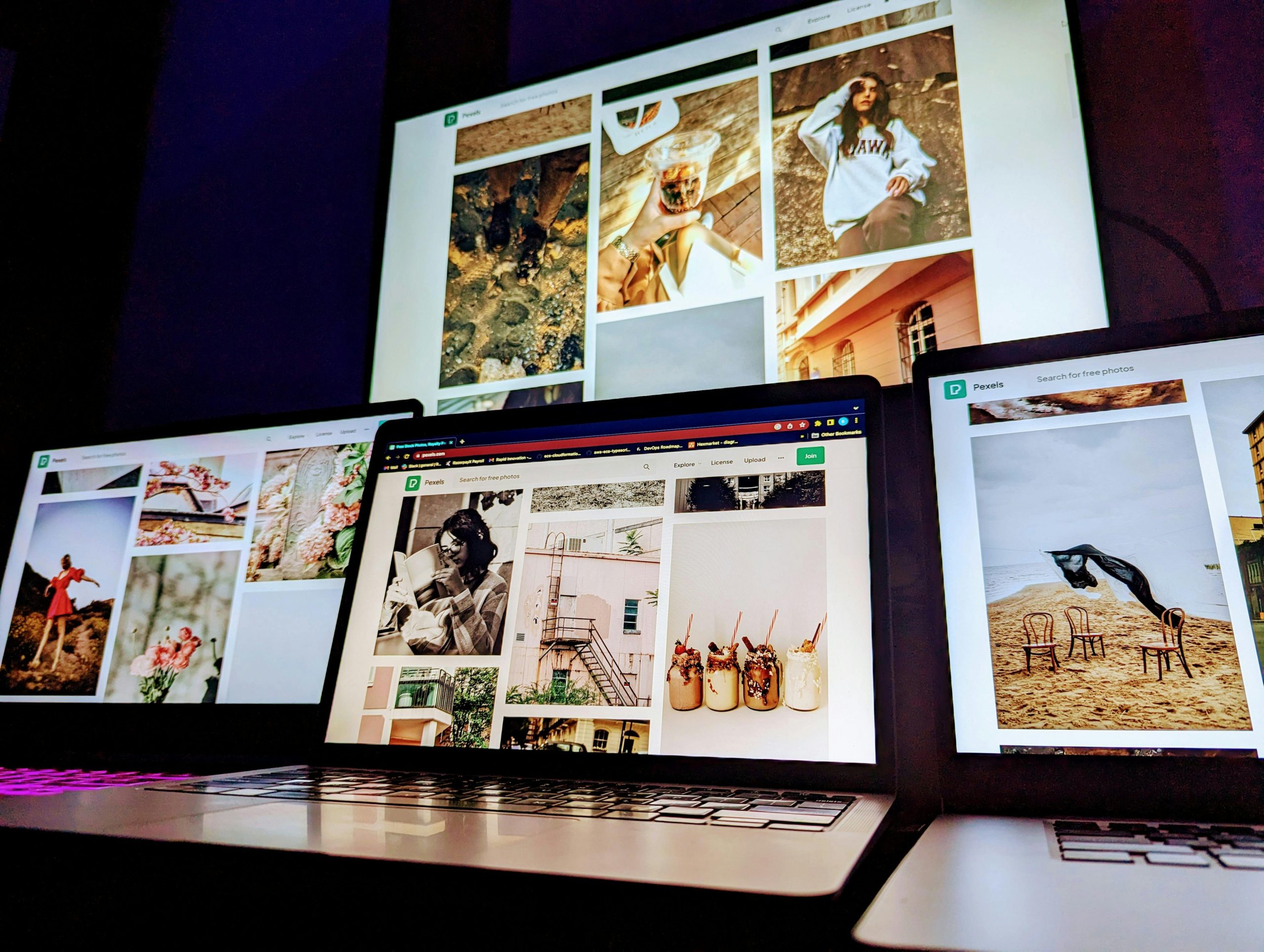 Array of laptops displaying various photographs in a dimly lit setting.